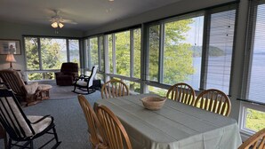 A covered patio with a dining table, chairs, and rocking chairs. - Stay 3 and play 4 free!!! (Dandridge)