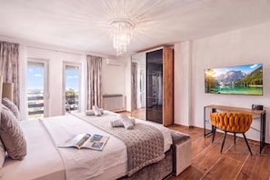 A modern bedroom with a large bed, a desk, and a TV displaying a mountain landscape. - Villa Natali With Pool And Sea View (Kraljevica)