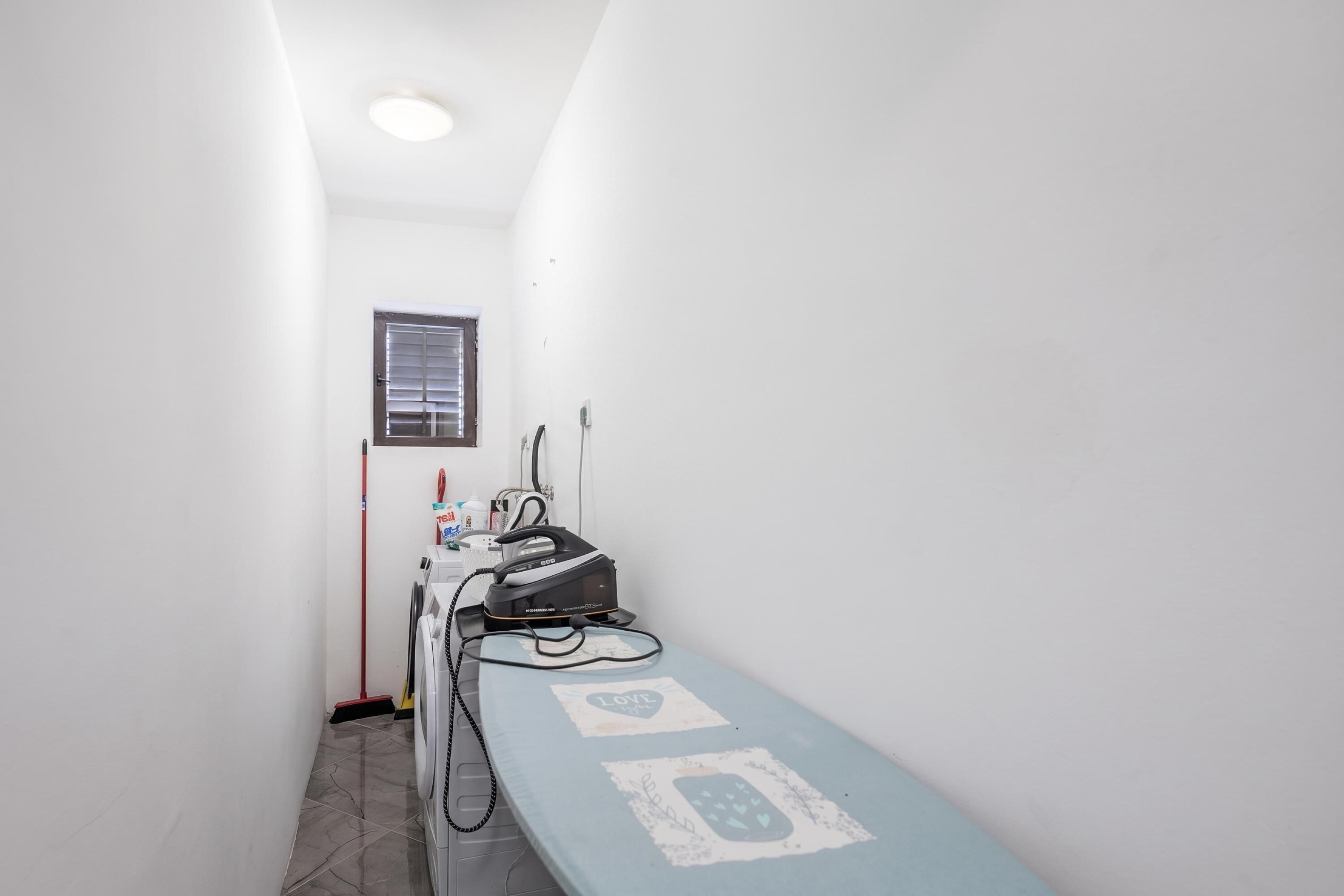 A narrow hallway with a window, a wall-mounted telephone, and a medical device on a table.