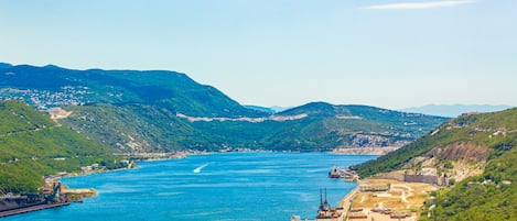 A coastal town with a river, hills, and a small harbor with boats.