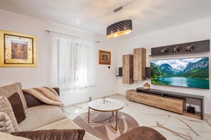 A modern living room with a sofa, a coffee table, a TV, and artwork on the walls. - Villa Natali With Pool And Sea View (Kraljevica)
