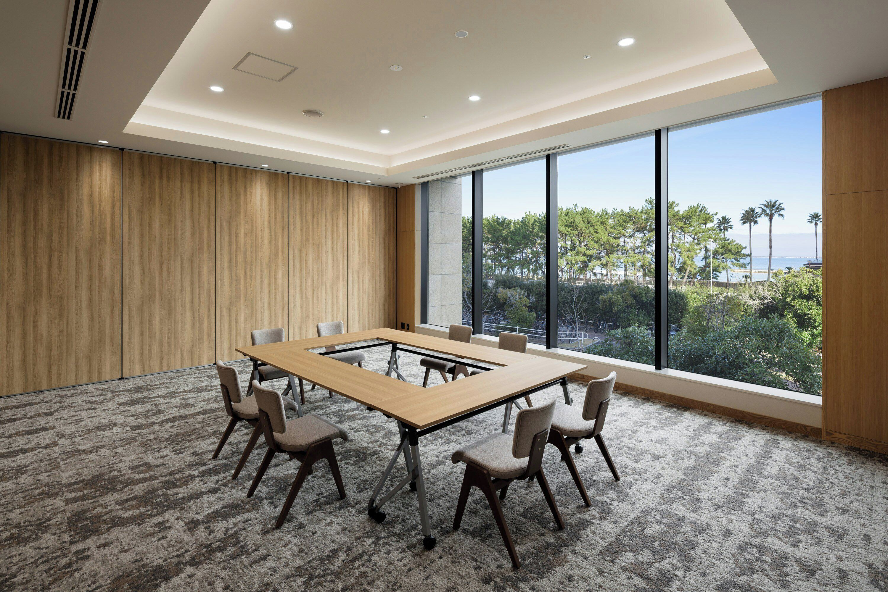 A conference room with a large table, chairs, and a view of the outdoors.