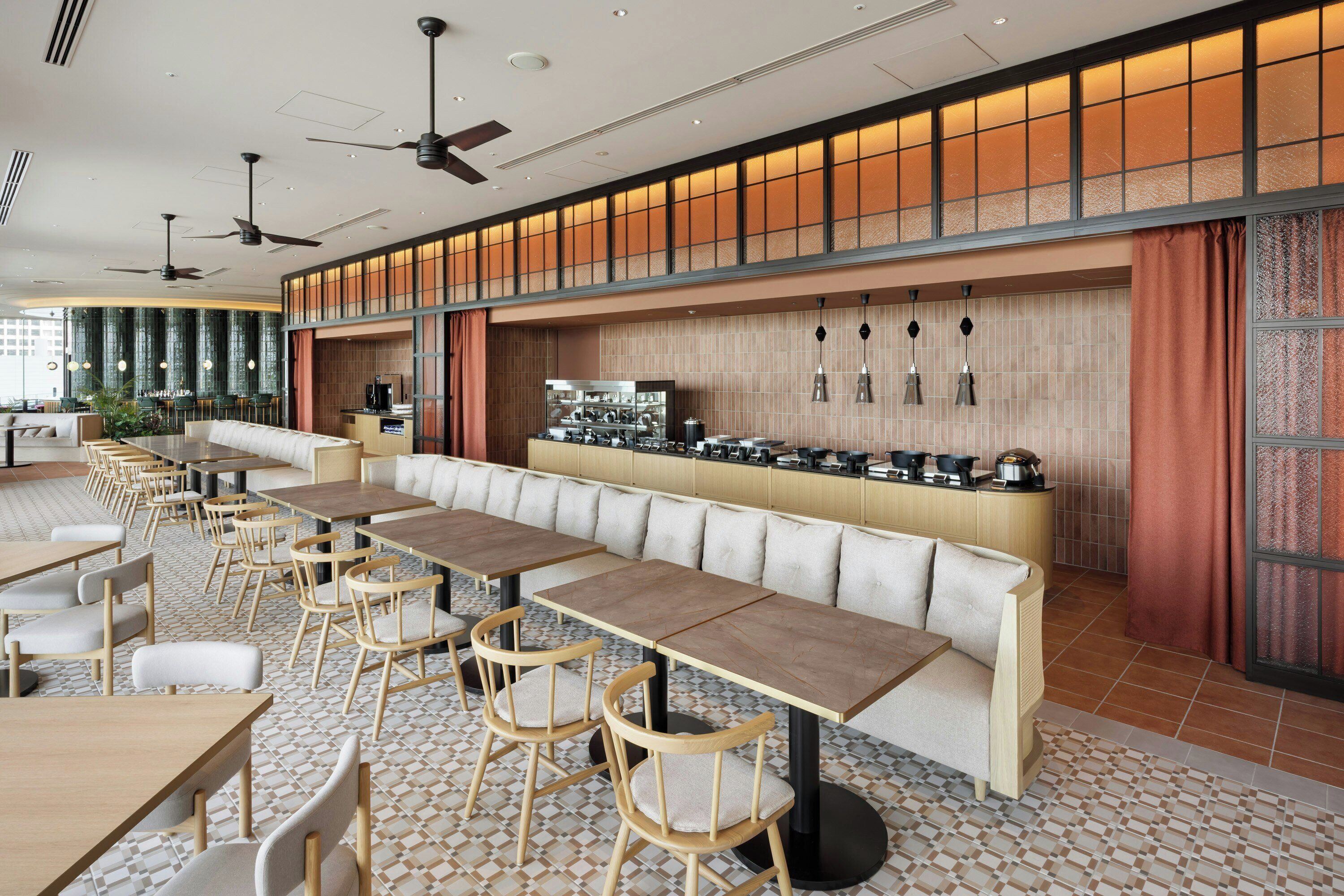 Un restaurante moderno con una barra larga, varias mesas y un techo alto con ventiladores.