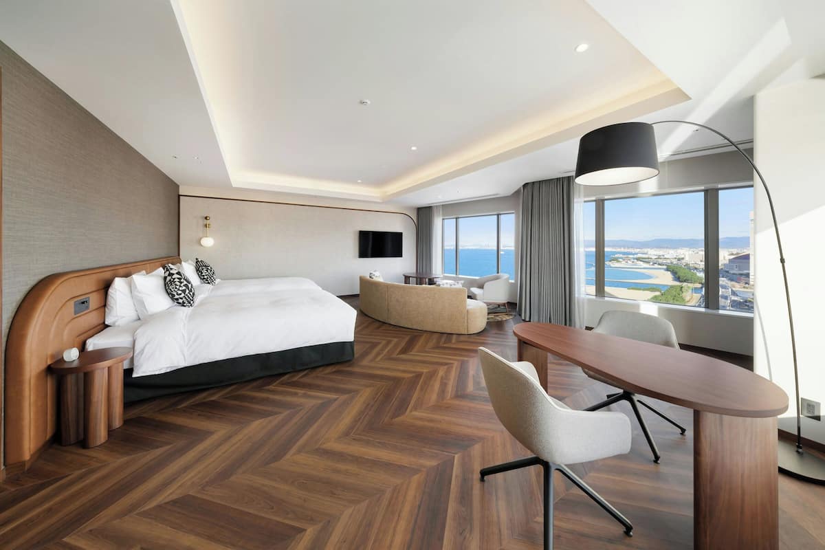 Ein modernes Hotelzimmer mit einem großen Bett, einem Schreibtisch und Blick auf die Stadt.