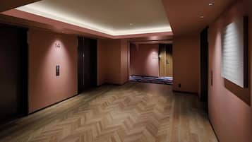Ein Hotelkorridor mit Fischgrätparkett, nummerierten Türen und einer Senkluftdecke.