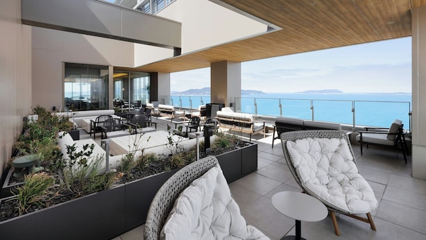 A rooftop terrace with seating, a view of the sea, and a modern architectural design. - Fukuoka Prince Hotel Momochihama (Fukuoka)