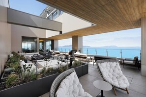 A rooftop terrace with seating, a view of the sea, and a modern architectural design. - Fukuoka Prince Hotel Momochihama (Fukuoka)