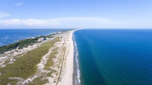An aerial view of a coastal area with a beach, buildings, and vegetation.
