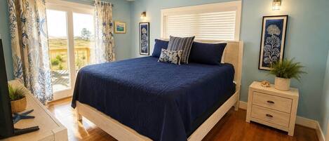 A bedroom with a bed, a nightstand, a ceiling fan, and a window with blinds.