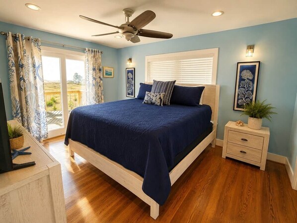 A bedroom with a bed, a nightstand, a ceiling fan, and a window with blinds.