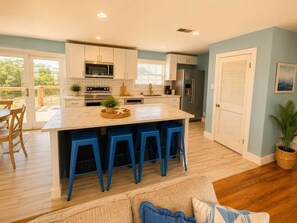 A modern kitchen with a central island, bar stools, and a dining area with a view.