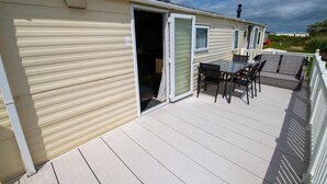 Une maison mobile avec une terrasse, une table et des chaises.