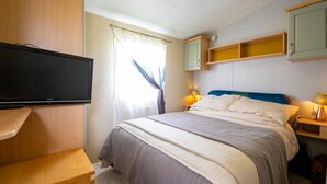 Une chambre à coucher avec un lit, des lampes de chevet, une télévision et une armoire.
