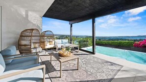 A modern outdoor lounge area with a pool, seating, and a view of the landscape.