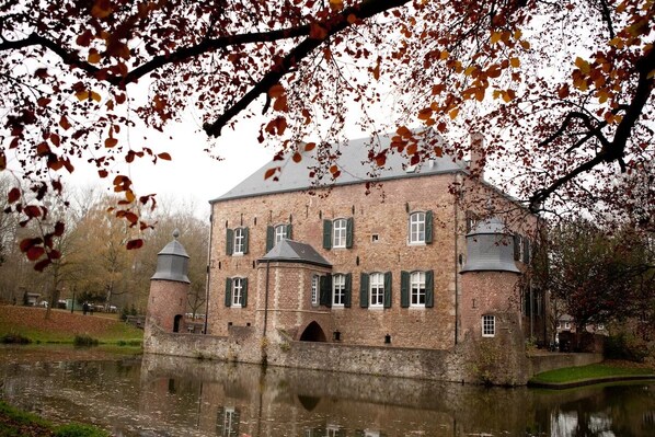 Stunning historic building with a prominent tower and turret, situated beside a serene body of water.