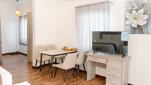 A modern hotel room with a dining area, a TV, and a painting of flowers on the wall. - Ba Tam Vu Sua (Ho Chi Minh City)