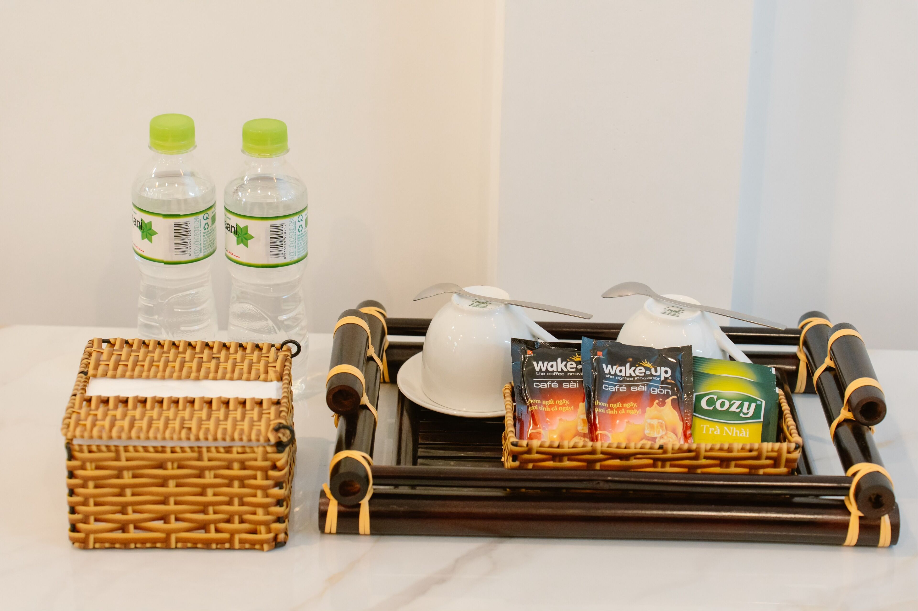 A tray with a bottle of water, a cup, a spoon, and two packaged coffee drinks.
