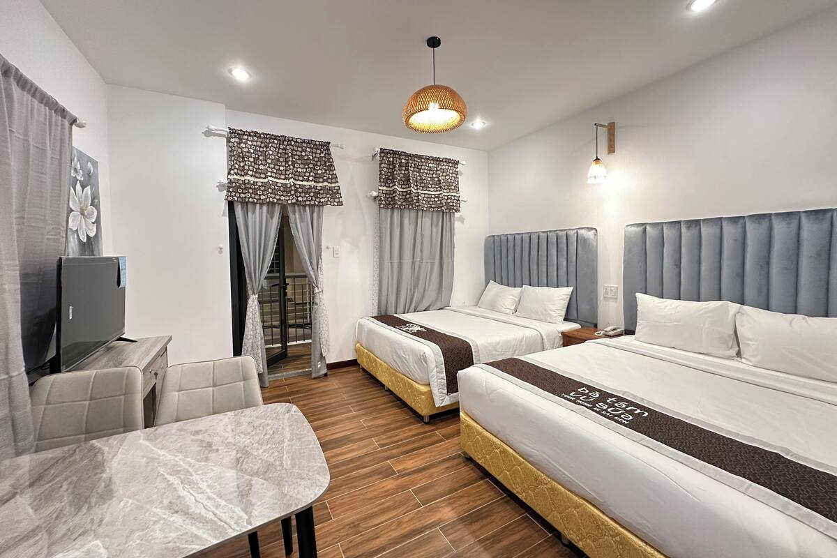 A hotel room with two beds, a TV, a table, and a chair.