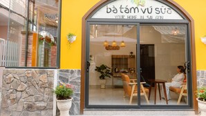A restaurant with a glass door, a stone wall, and potted plants. - Ba Tam Vu Sua (Ho Chi Minh City)