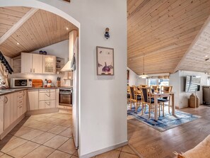 Enjoy cooking in the well-equipped kitchen with a central island, microwave, and oven, adjacent to a dining area with a wooden table and chairs.