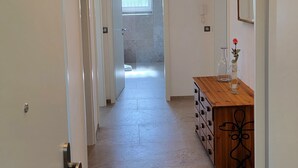 Un couloir avec une armoire en bois et un miroir, qui mène à une salle de bain avec une douche.