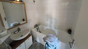 Et badeværelse med en hvid vask, spejl og badekar.