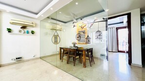 Un comedor moderno con separador de vidrio, mesa de madera, sillas y jaulas decorativas.