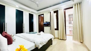 Una habitación de hotel con cama, televisión y balcón con cortinas.