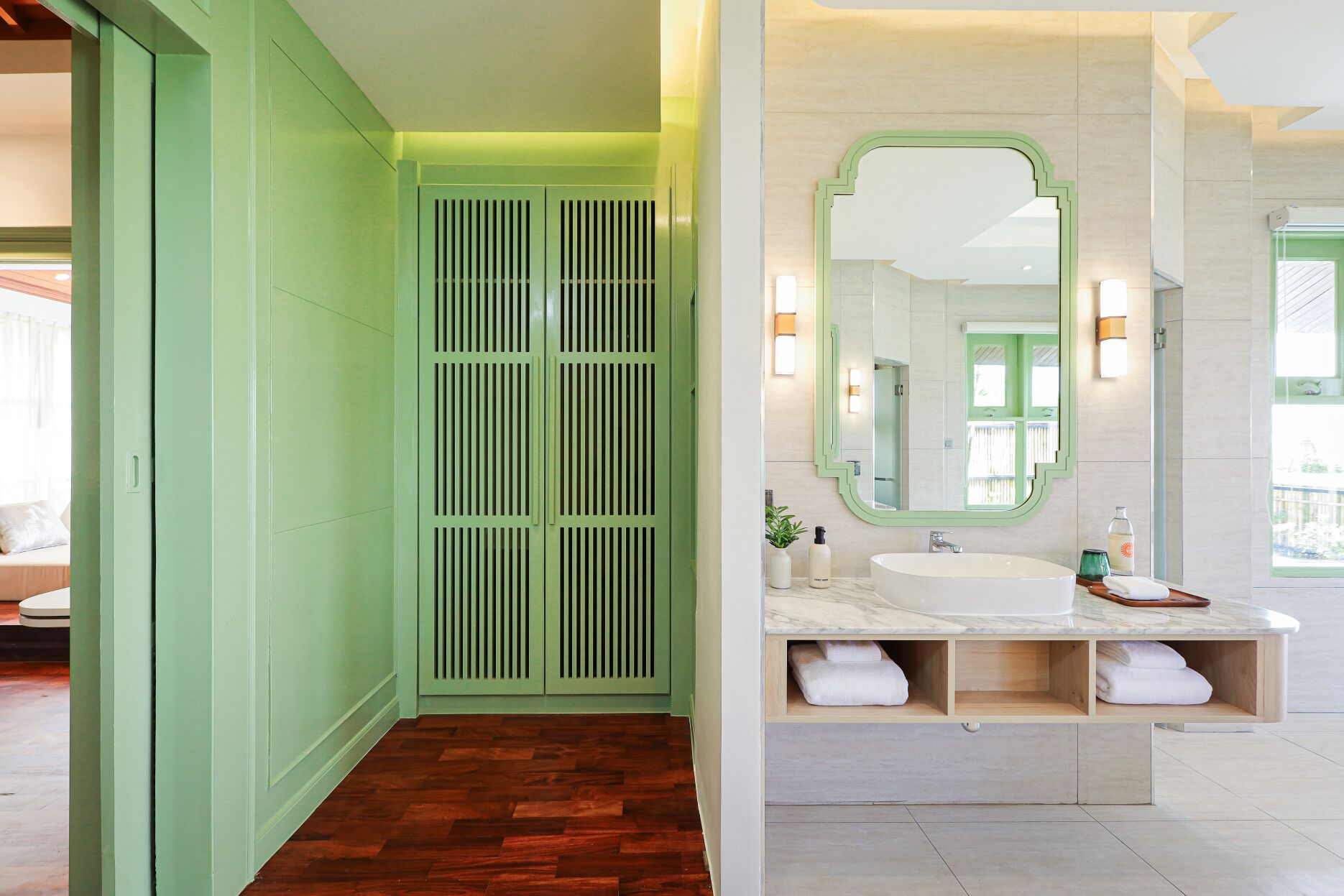A bathroom with a green vanity, a large mirror, and a marble sink.