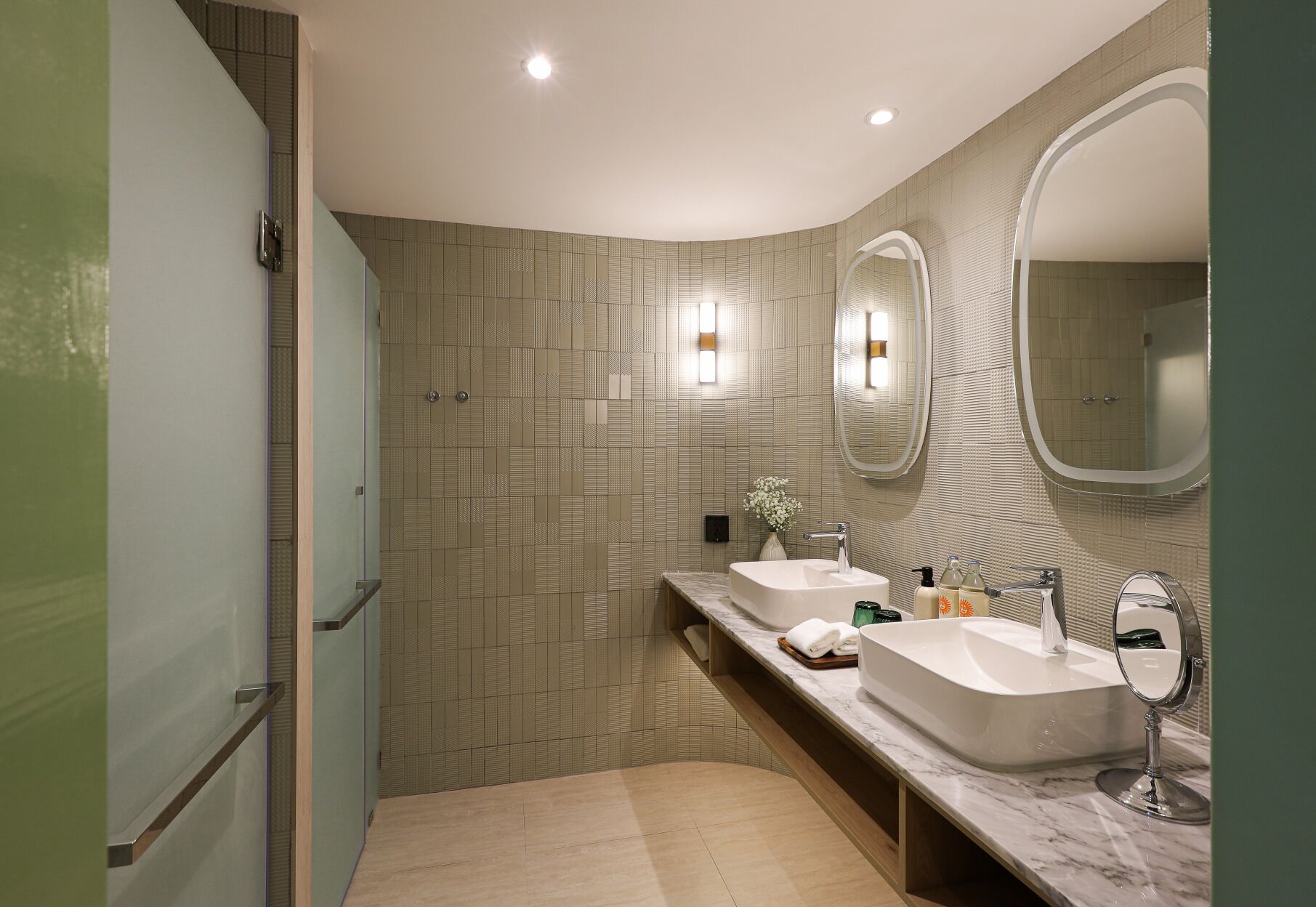A modern bathroom with two sinks, a large mirror, and a shower area.