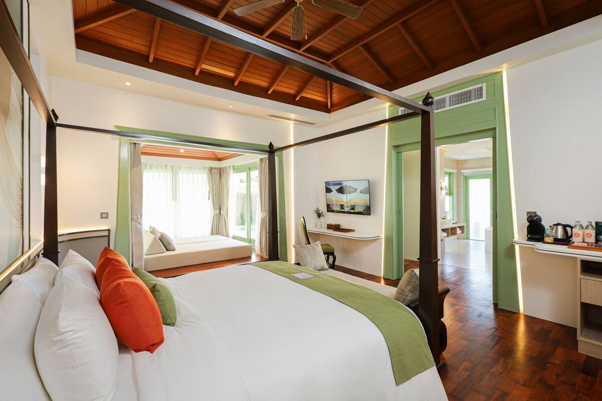 Un dormitorio espacioso con una cama grande, un escritorio y vistas al jardín.