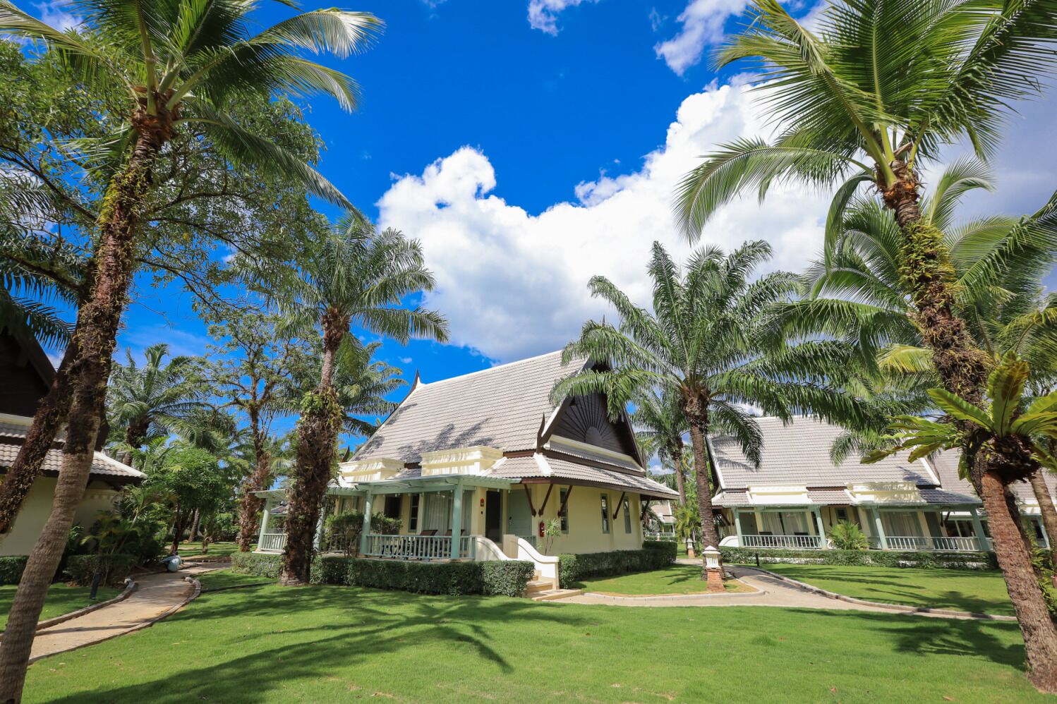 A traditional-style building with a tiled roof, surrounded by lush palm trees and well-maintained lawns.