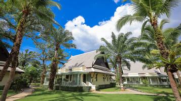 A traditional-style building with a tiled roof, surrounded by lush palm trees and well-maintained lawns.