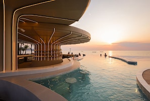 Une piscine à débordement moderne, dotée d’un bar et offrant une vue imprenable sur le coucher de soleil.
