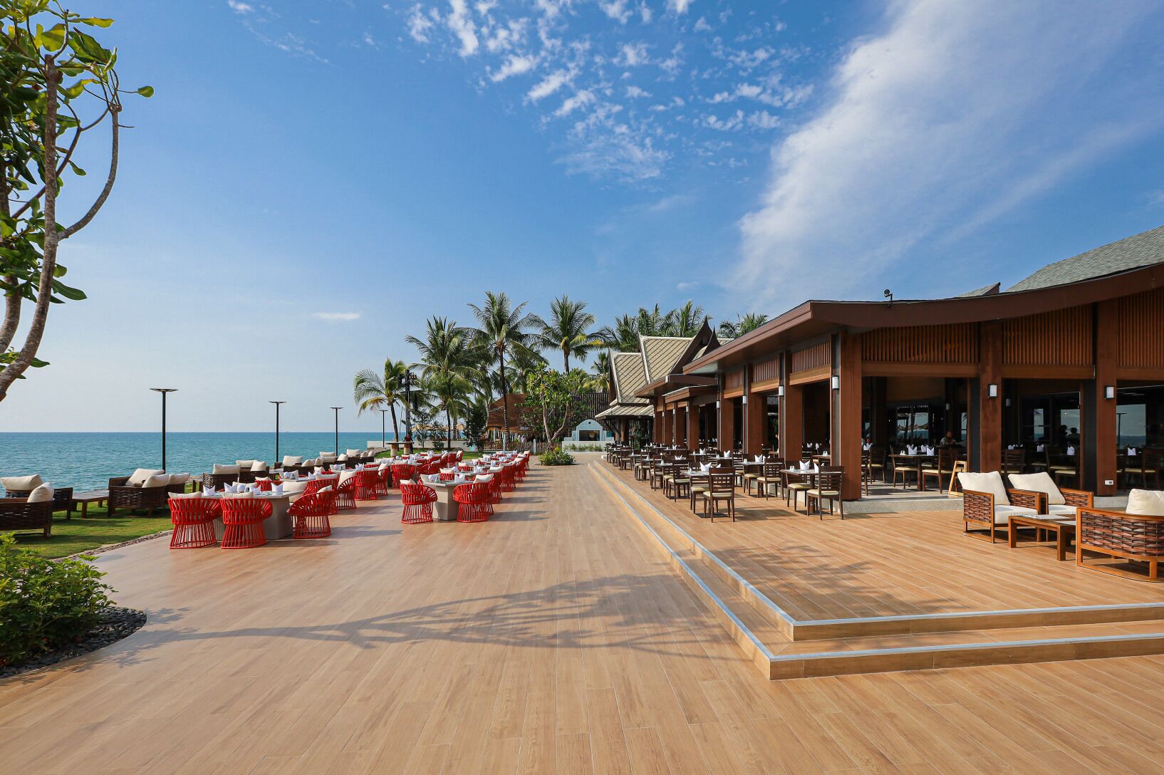 Un resort sulla spiaggia con aree salotto all'aperto e una zona pranzo coperta.