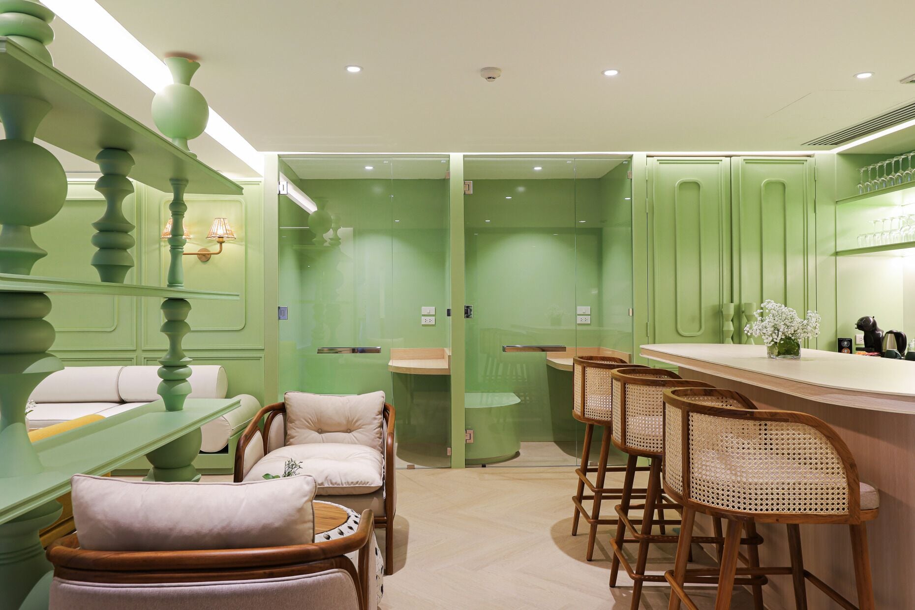 Un interior con decoración verde, una zona de bar, asientos acolchados y una barra.