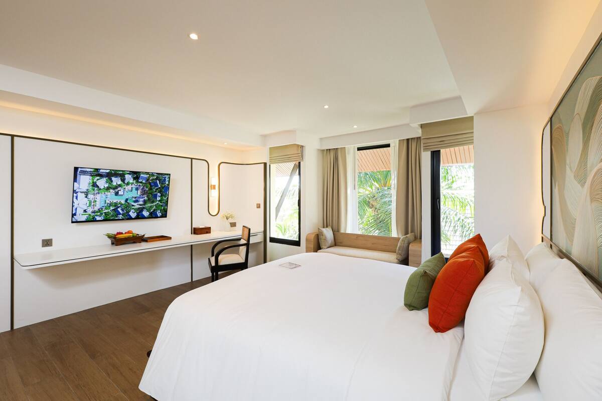 Una habitación de hotel moderna con una cama grande, un escritorio y un televisor en la pared.