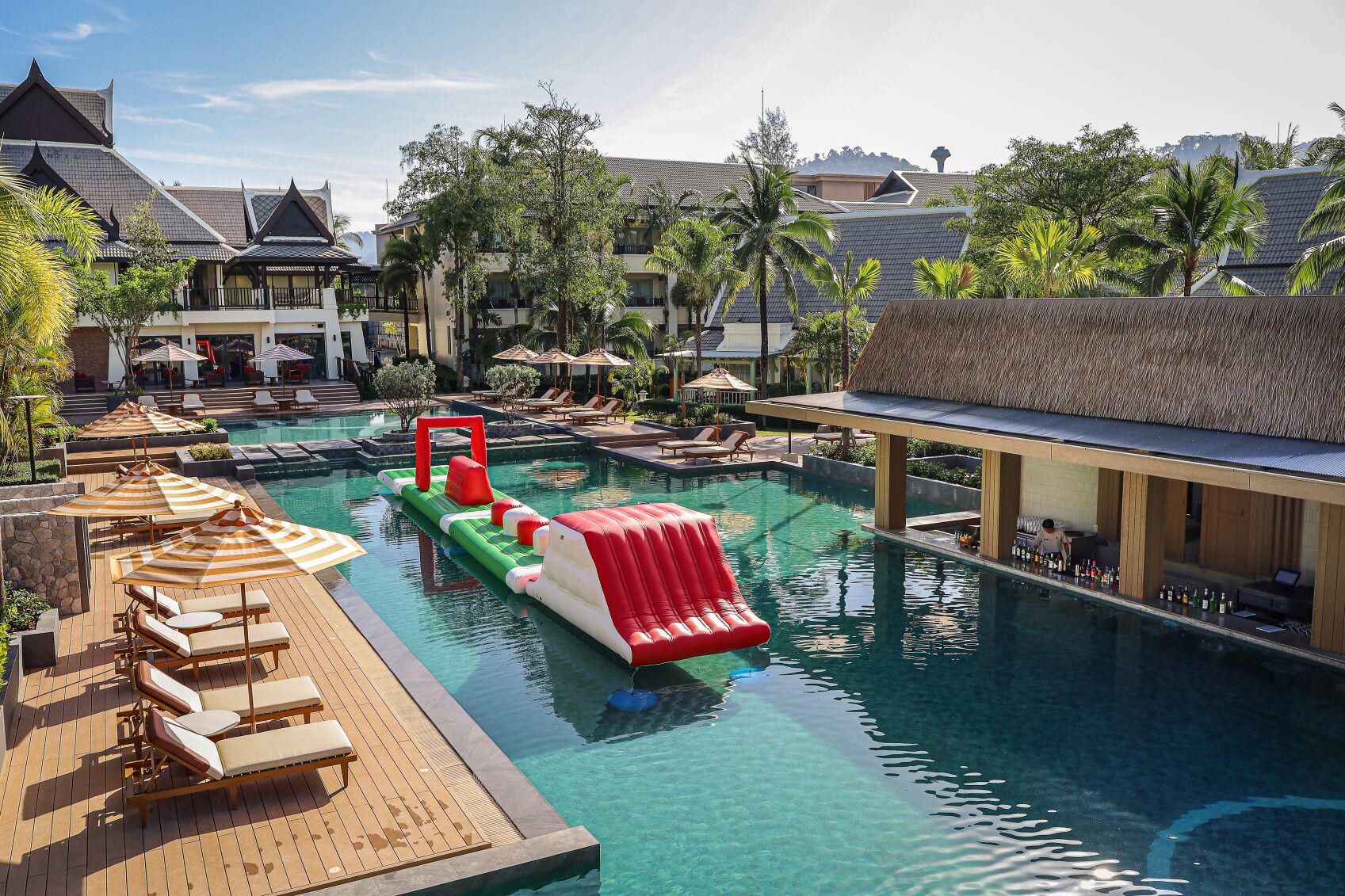 Piscina de resort con sillas de descanso, un tobogán de agua y zona de bar.