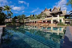 Un complexe hôtelier doté d’une piscine à eau cristalline, de chaises longues et d’un cadre tropical.