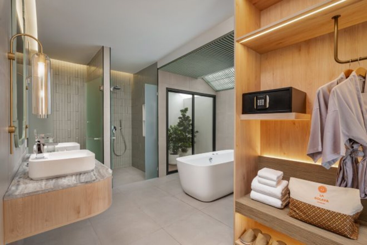 A modern bathroom with a freestanding bathtub, a vanity with a large mirror, and a towel rack with neatly folded towels.