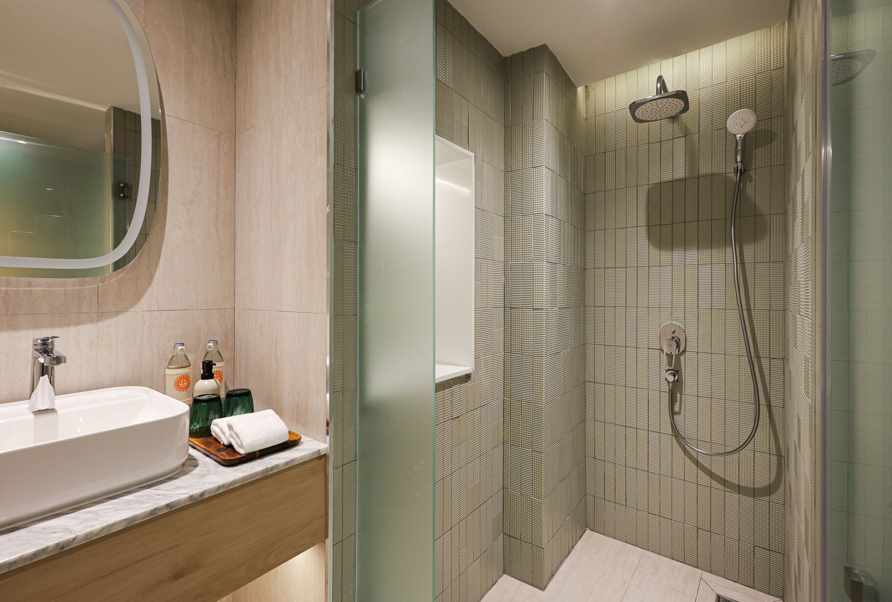 A modern bathroom with a glass-enclosed shower, a sink with a marble countertop, and a mirror above the sink.