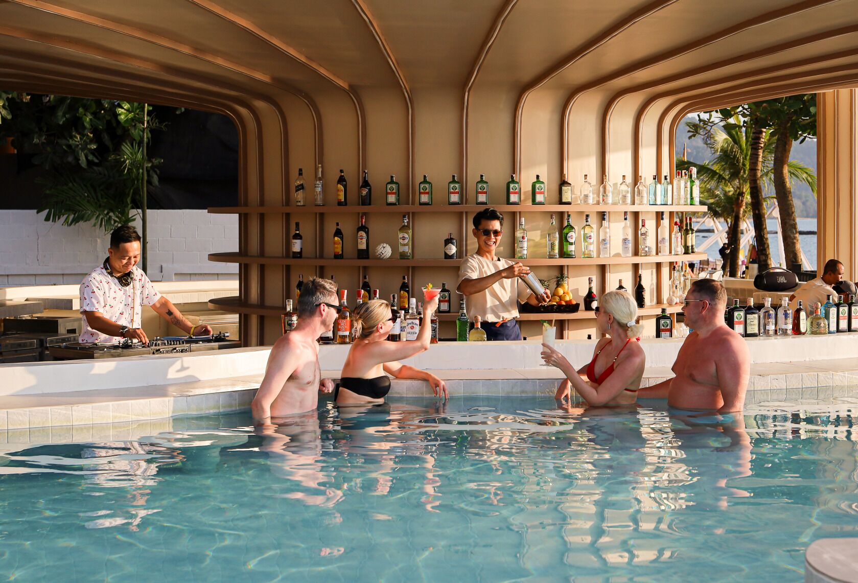 A poolside bar with a bartender, guests relaxing in the pool, and a variety of bottles on shelves.