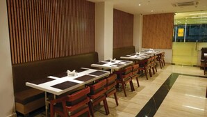 A restaurant with long wooden benches and tables, a tiled floor, and a modern interior design. - Park Niveda (Vijayawada)