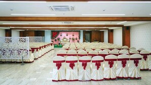 A large hall with rows of chairs, a stage with floral decorations, and a wooden ceiling. - Park Niveda (Vijayawada)