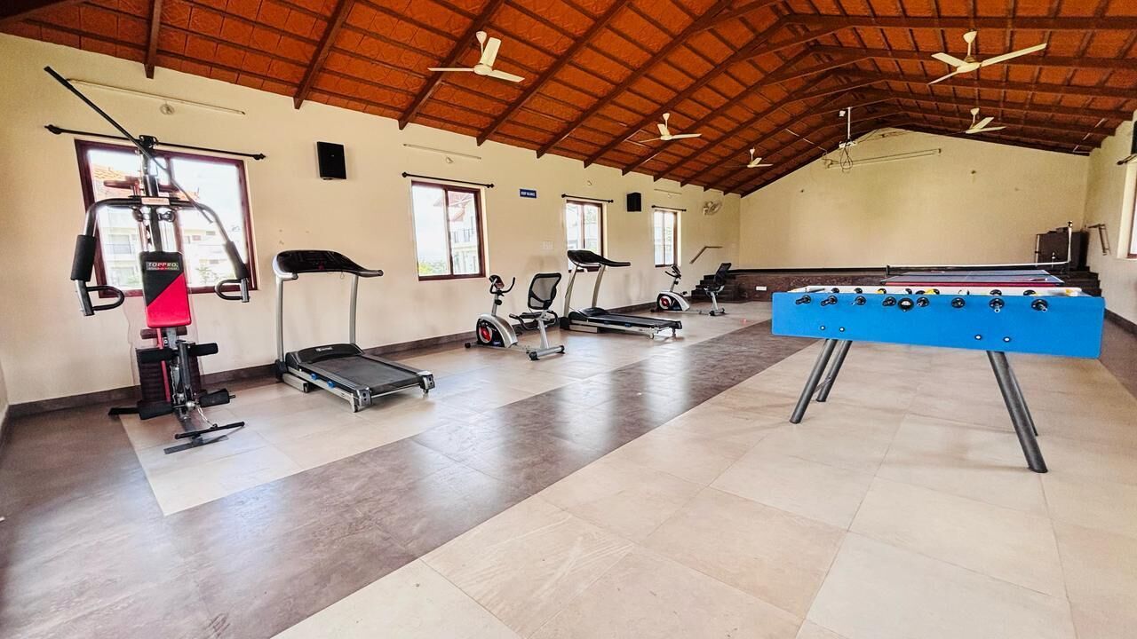 A gym with exercise equipment, a foosball table, and large windows.
