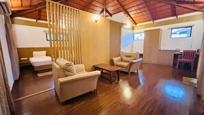 Una habitación amplia con suelo de madera, un sofá, una silla y una pequeña mesa.