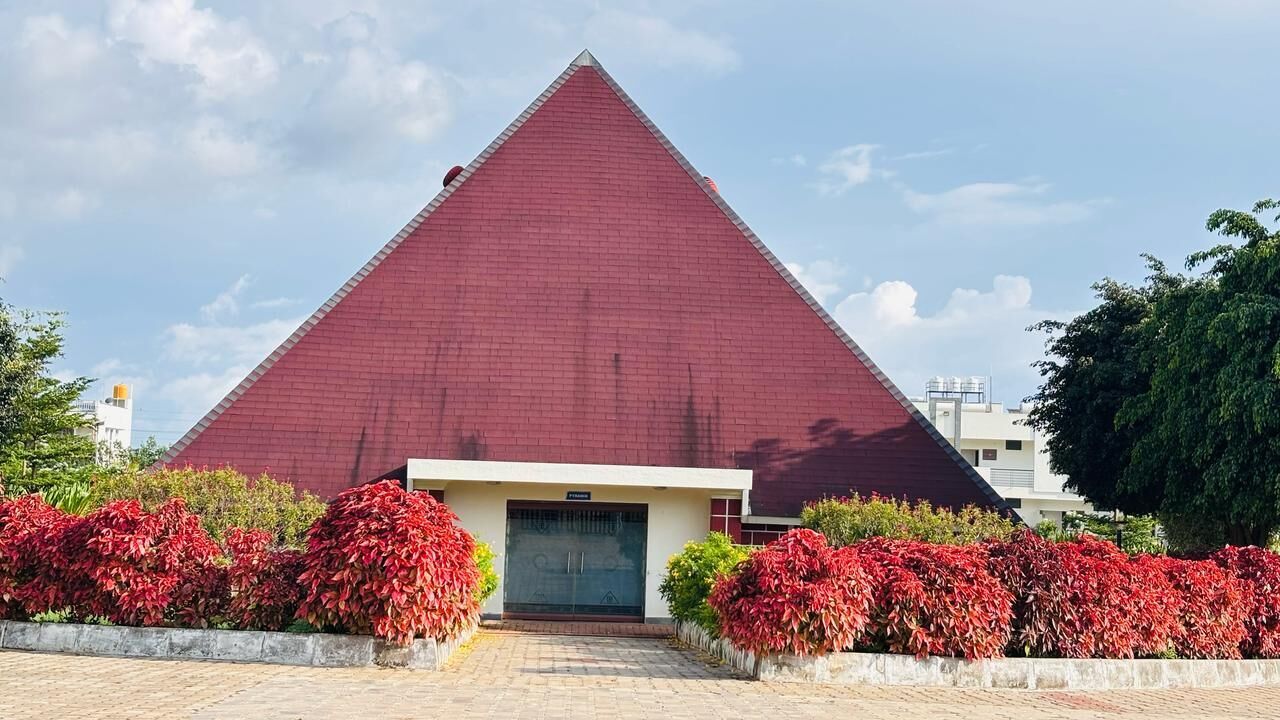 Ein pyramidenförmiges Gebäude mit rotem Dach, umgeben von roten Blättern.