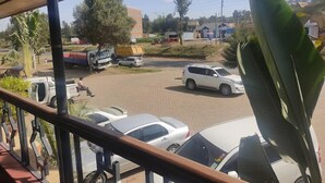 Un estacionamiento con varios coches y un SUV blanco. Se ven árboles y edificios al fondo.