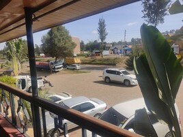 Un estacionamiento con varios coches y un SUV blanco. Se ven árboles y edificios al fondo.
