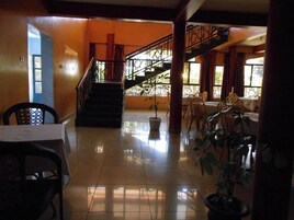 Un vestíbulo amplio con una escalera, un comedor y varias plantas en macetas.